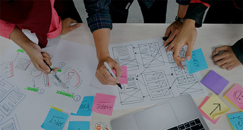 A small team gathered around a laptop, stressed and multitasking to plan a project together.